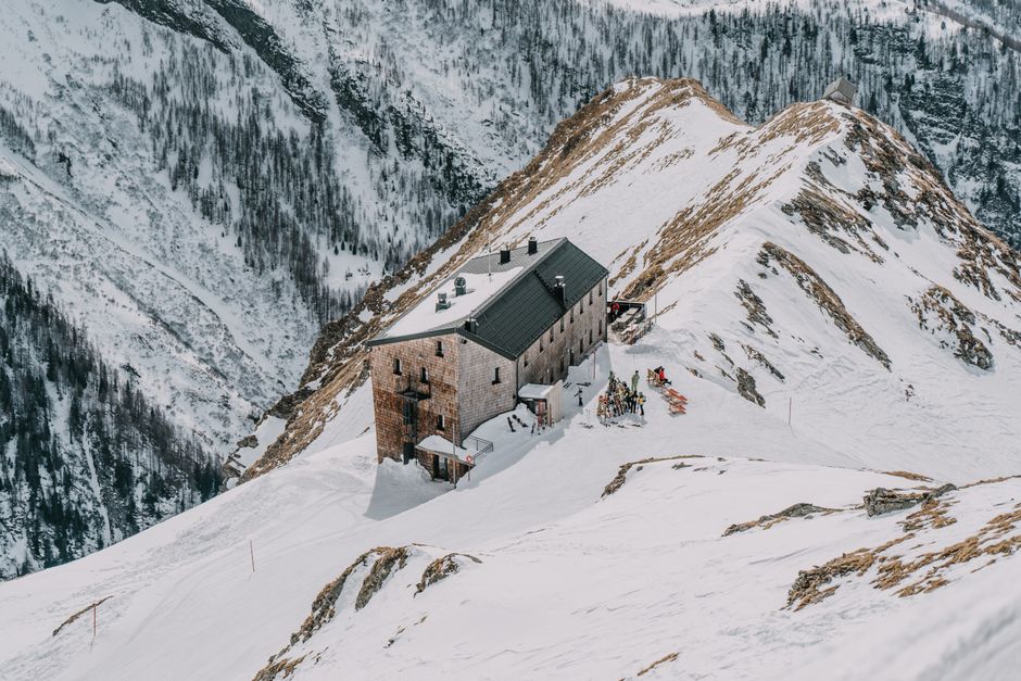 Wooden cabin nestled in a snowy alpine mountain setting, perfect winter retreat.