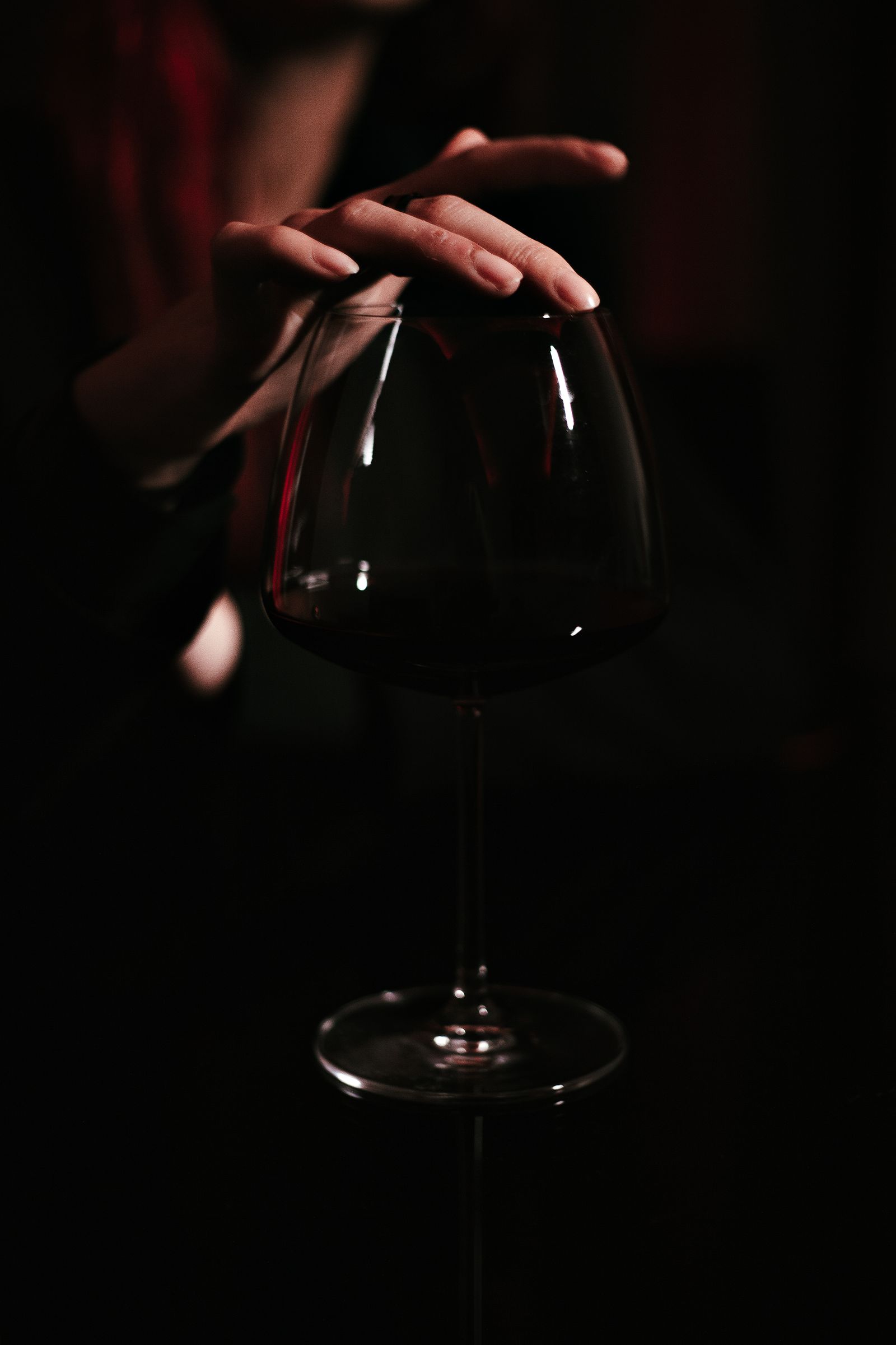 Copa de vino tinto sostenida sobre un fondo oscuro
