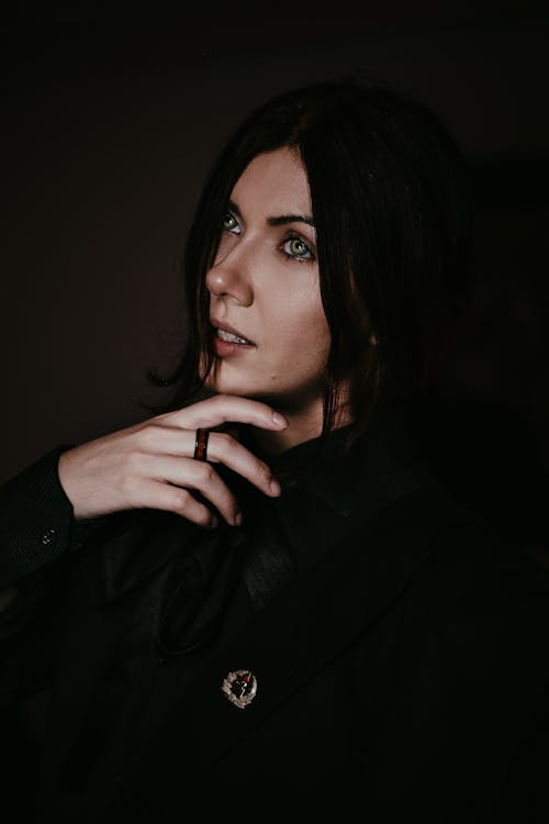 Brunette Woman in Black Clothes with Hand under Chin
