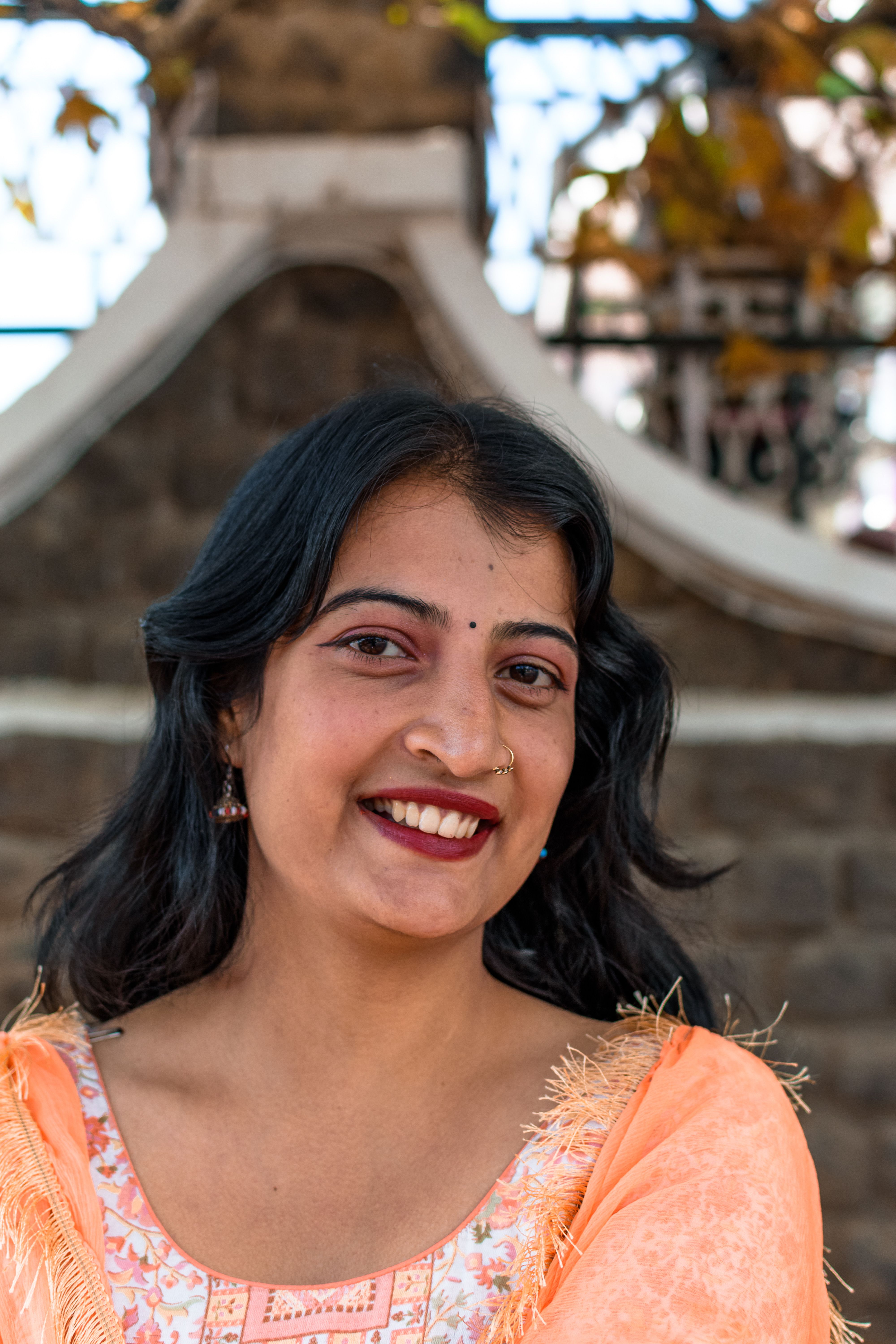 Portrait of a smiling woman with a nose ring and red lips, wearing traditional attire.
