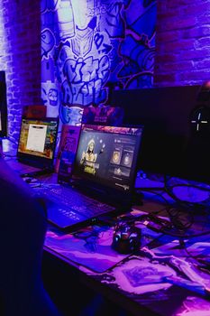 A dynamic gaming station with laptops and accessories under vibrant purple lighting, capturing the essence of contemporary gaming technology.