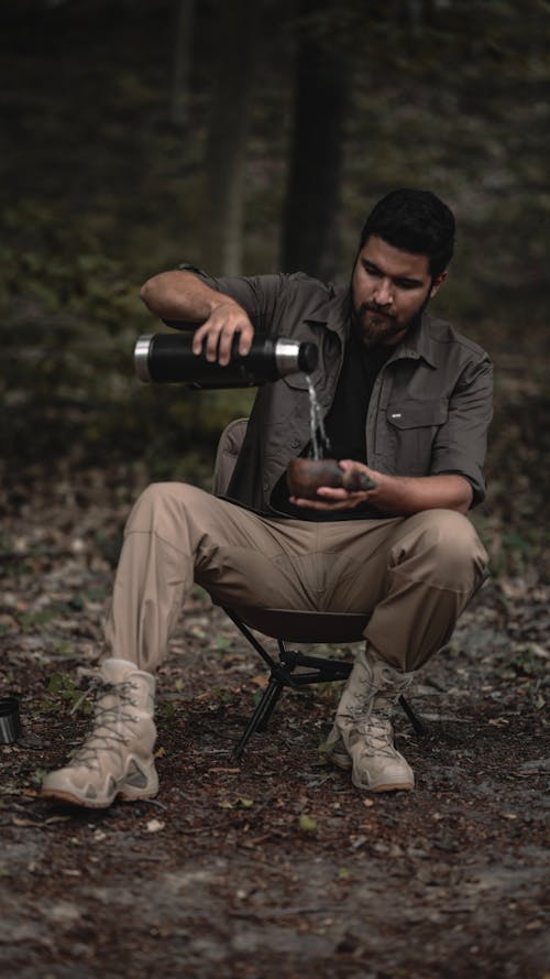 Bearded Man Pouring Water in Cup at Campsite