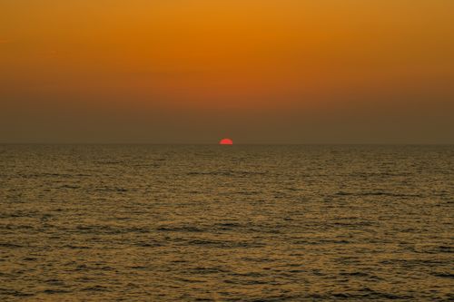 Free Tranquil sea and vibrant orange sky create a serene sunset at the horizon. Stock Photo