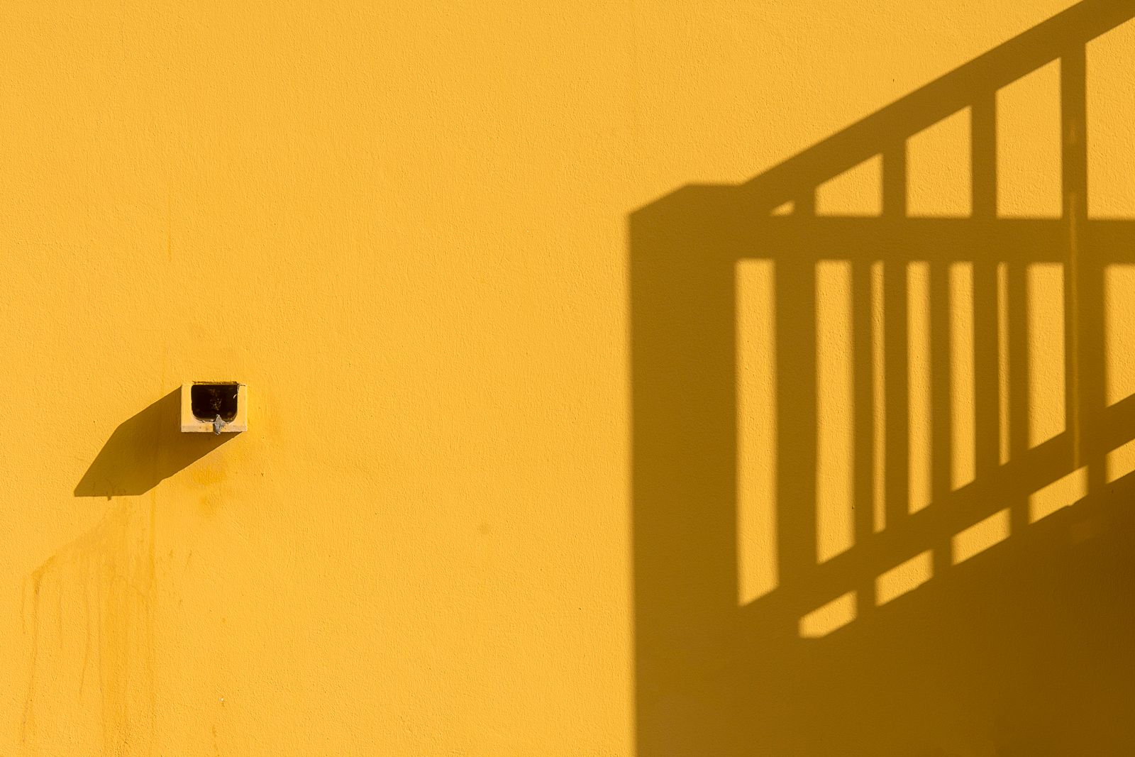 Sunlit yellow wall with a staircase shadow — photo by Jan van der Wolf on Pexels