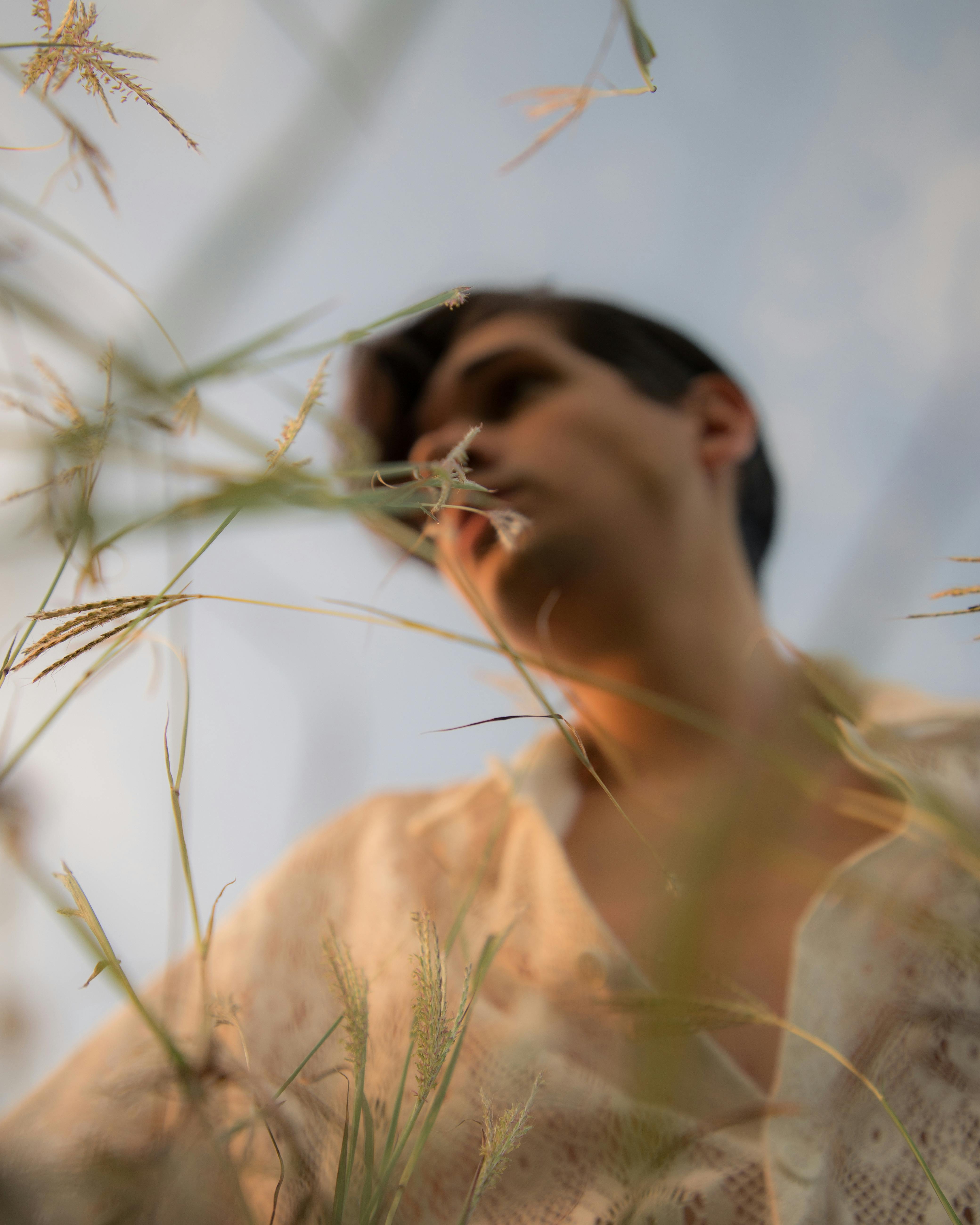 Creative low-angle shot of a man seen through plants with a dreamy focus effect.
