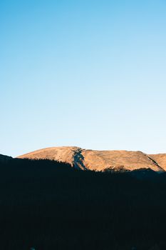 Sunlit mountain peak under a clear sky in Kananaskis, Alberta, Canada.