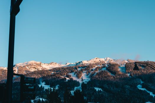 Explore the stunning winter landscape of Whistler with snow-covered mountains and clear blue skies.