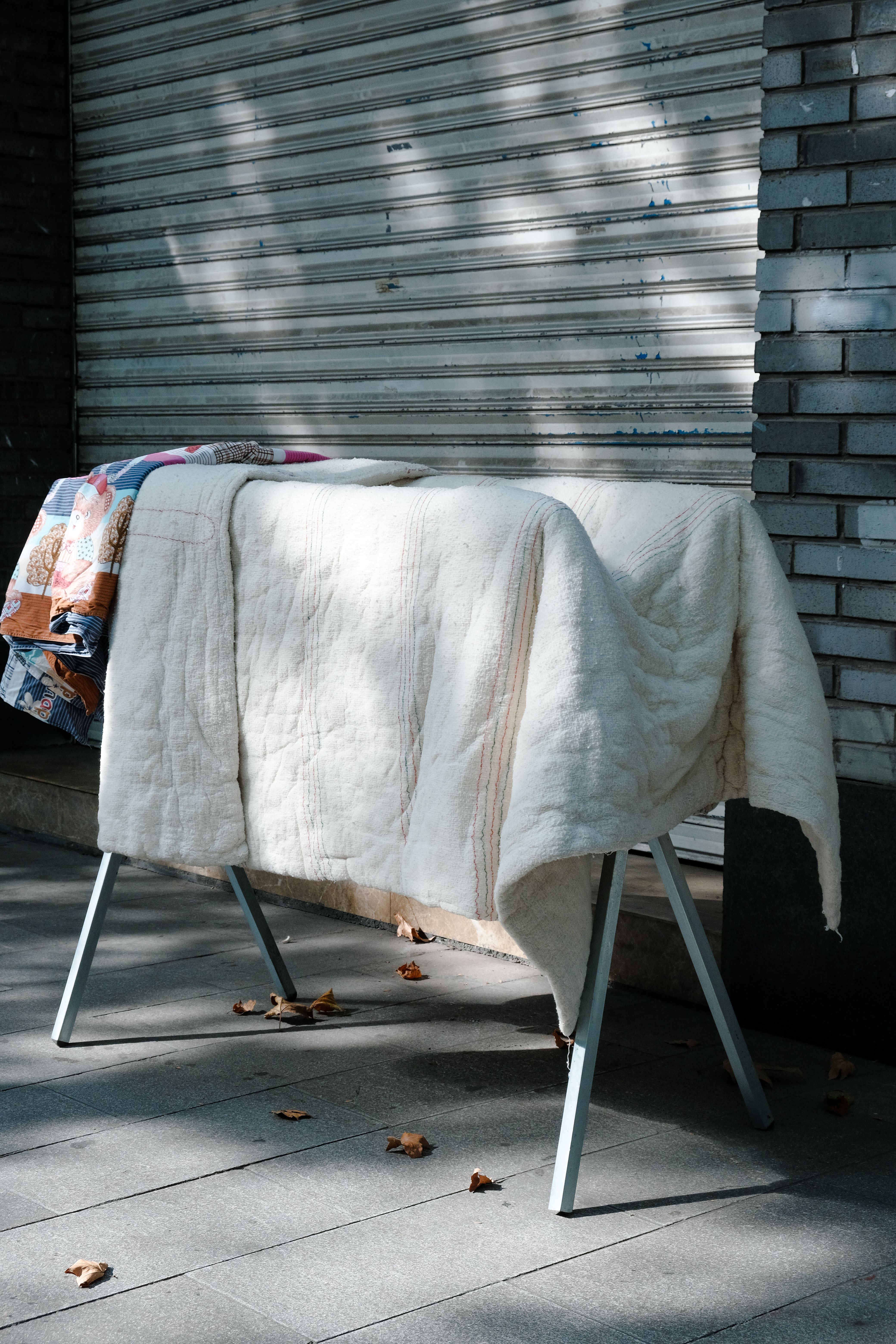 Linen drying outside on a clotheshorse in the city, sunlit with urban backdrop.