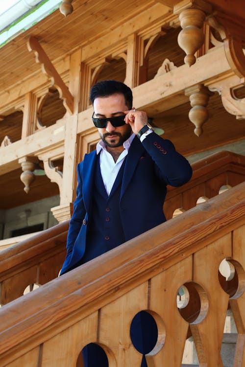 Elegant Man in a Suit and Sunglasses Walking Down the Stairs of a Wooden Building 
