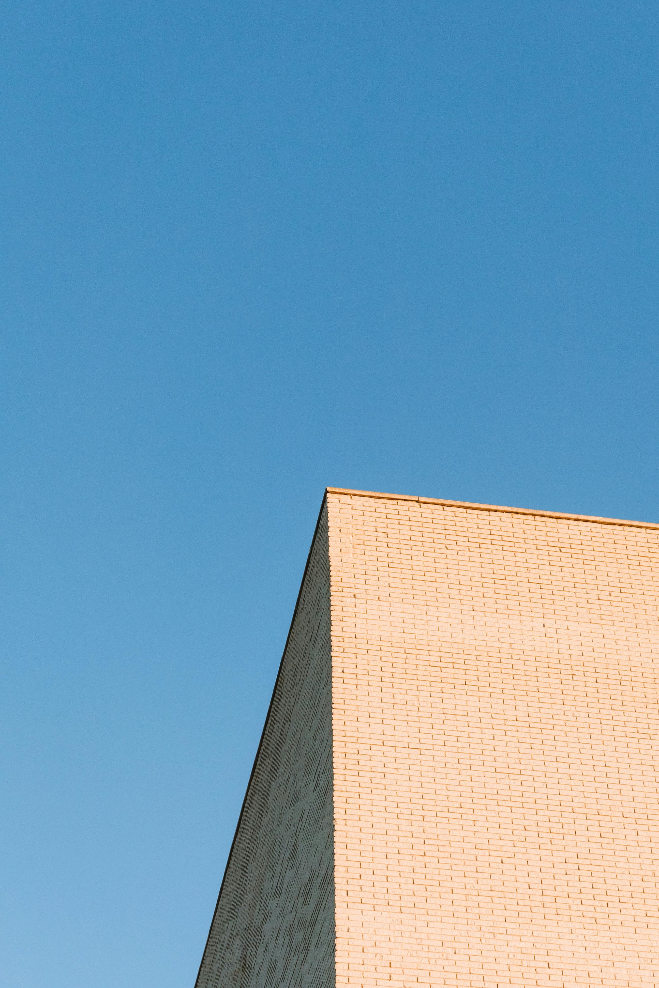 A minimalist white building's corner under a clear blue sky, perfect for architecture enthusiasts.
