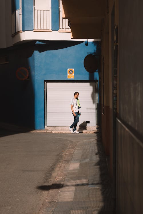 Candid Photo of a Man Walking in the Alley between Buildings 