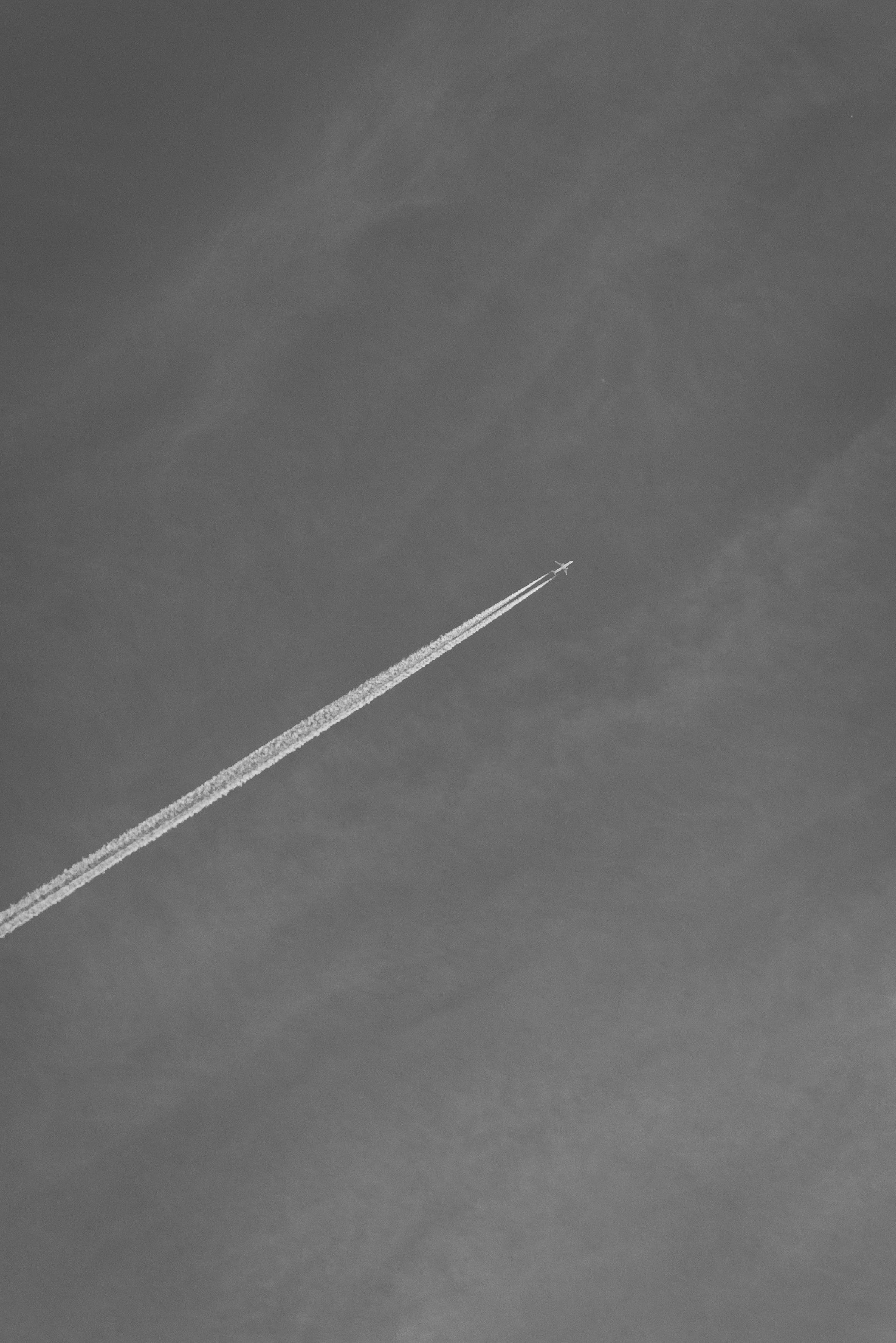 High-altitude shot of a jet with a long contrail against a clean, muted sky.