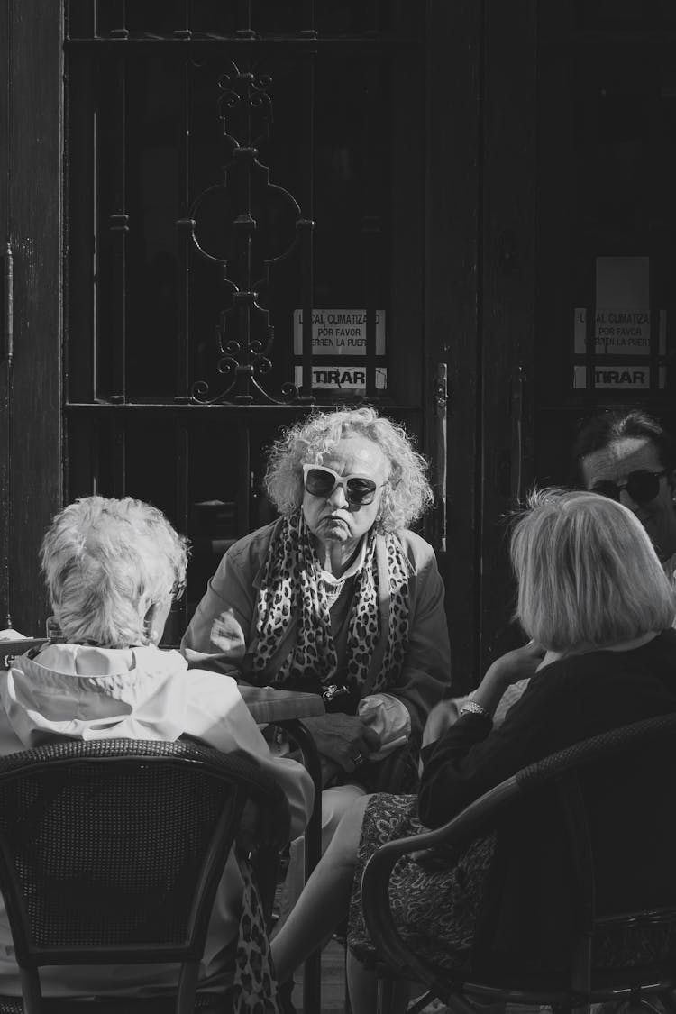 A Group Of Elderly Women Sitting At The Table Outside 