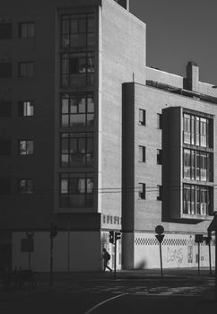 Black and white cityscape of modern buildings with a person walking.