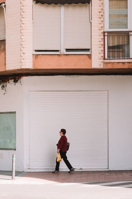 Woman walking with bags in the city, modern architecture background.