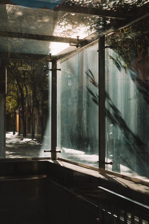 Free A sunlit city alley showcases elegant glass panels casting shadows, creating a serene urban scene. Stock Photo