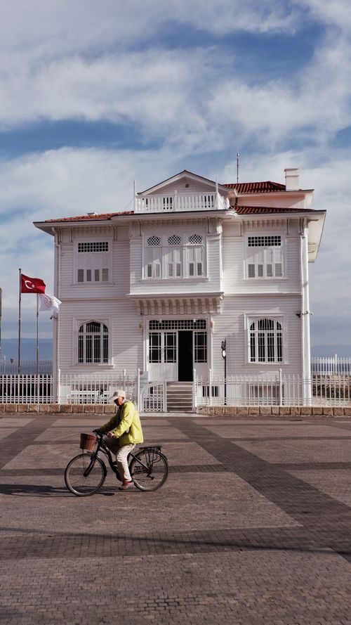 Free Elderly cyclist rides past the Mudanya Armistice House in Turkey on a sunny day. Stock Photo