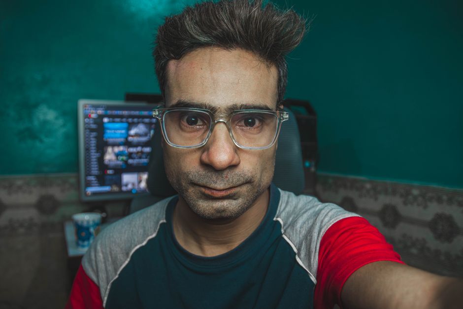 Portrait of a man with eyeglasses in a home office, showcasing a casual and focused look.