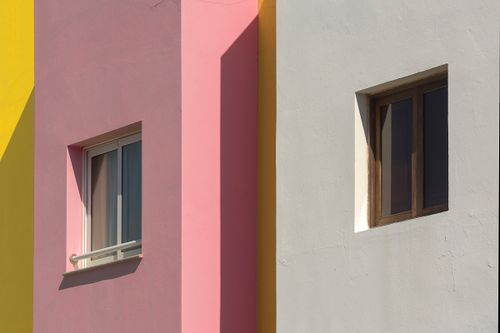 Free A vibrant facade showcasing geometric shapes and varied window designs under sunlight. Stock Photo