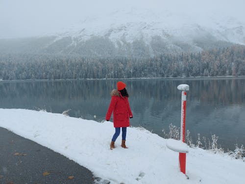 Brunette Woman in Red Coat Standing on Lakeshore