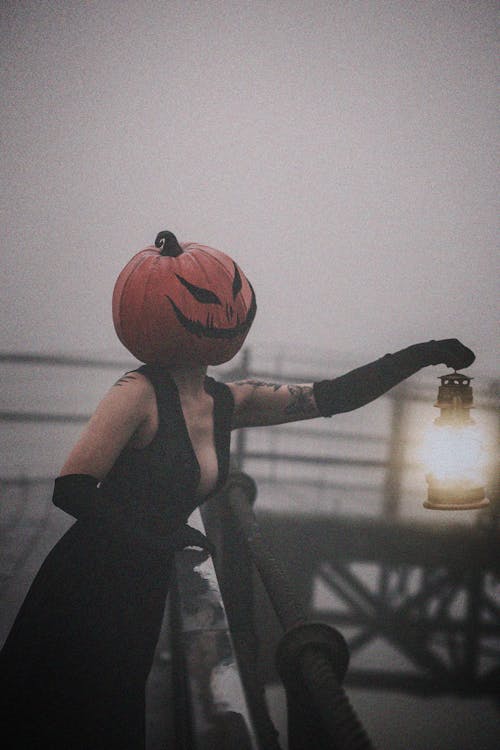 Woman with Pumpkin Mask Posing with Lantern in Fog