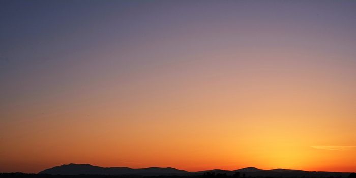 A breathtaking sunset in Penrith, UK with mountains silhouetted against vibrant orange hues.