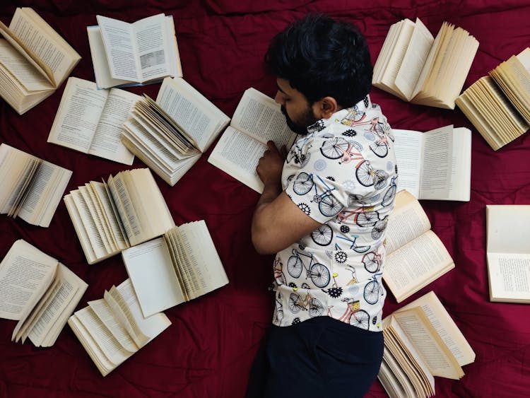 Man Lying Down Among Books And Reading