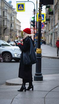 Stylish woman in red beret crossing a street in Saint Petersburg, Russia. Urban fashion and travel.