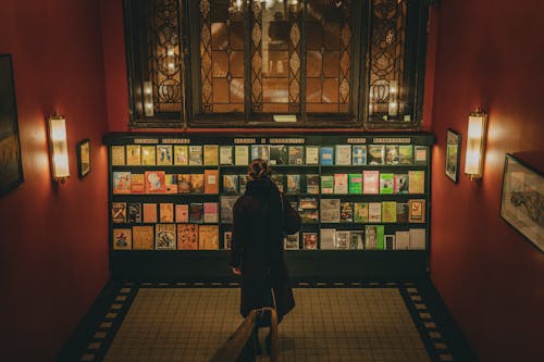 A person walking through a library with books on the shelves