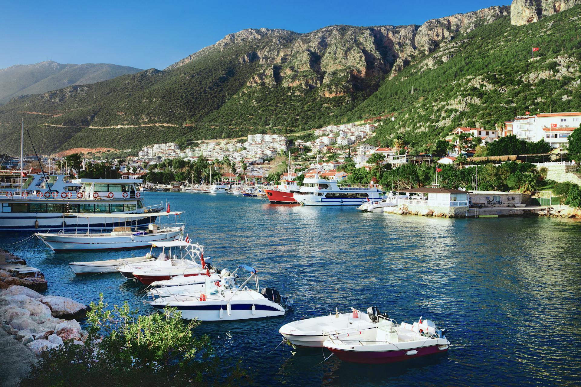 Beautiful marina with moored yachts and a coastal town in Kaş, Antalya, Turkey on a sunny summer day.