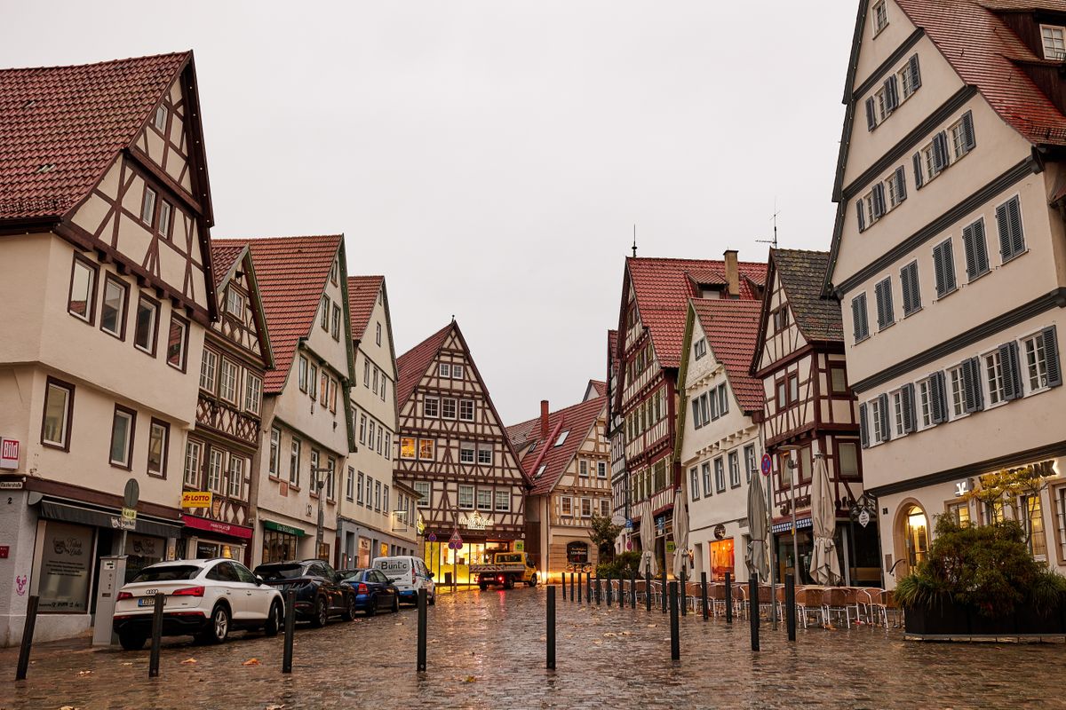 Half-timbered houses lining a wet cobbled street at dusk
