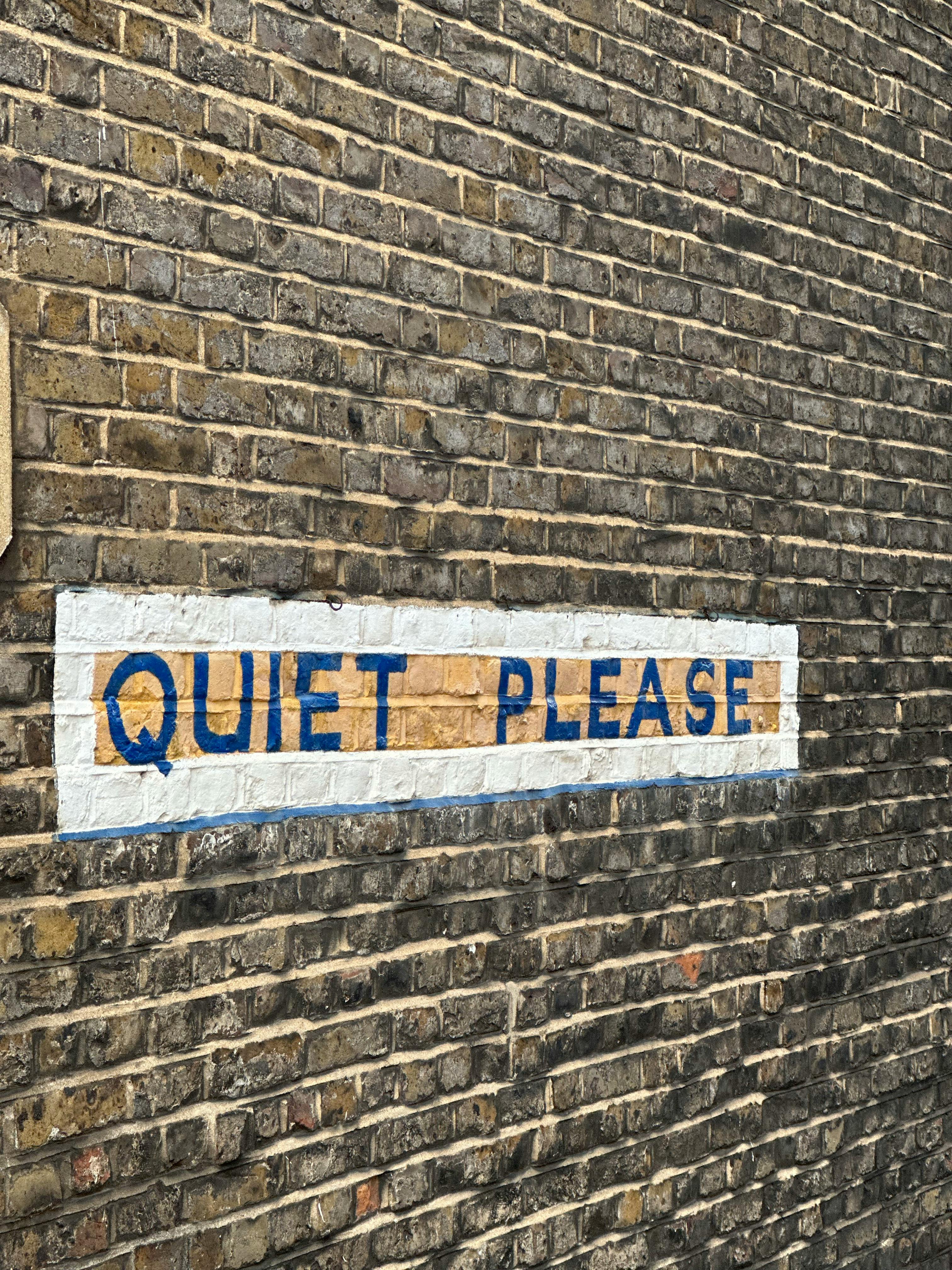 Free Close-up of a brick wall with a painted 'Quiet Please' sign, offering copy space. Stock Photo