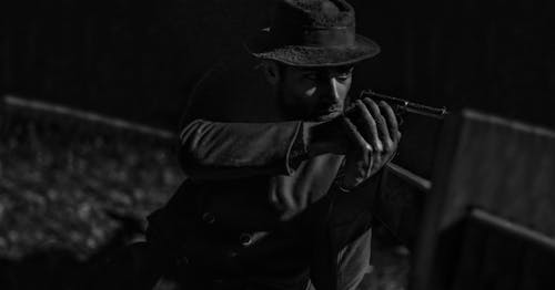 Man in Hat Aiming with Pistol in Black and White