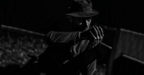 Free Mysterious man in noir style aiming a pistol with intense focus. Stock Photo