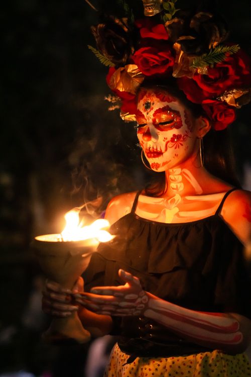 Free Woman with Catrina makeup holding candle, celebrating Day of the Dead at night. Stock Photo