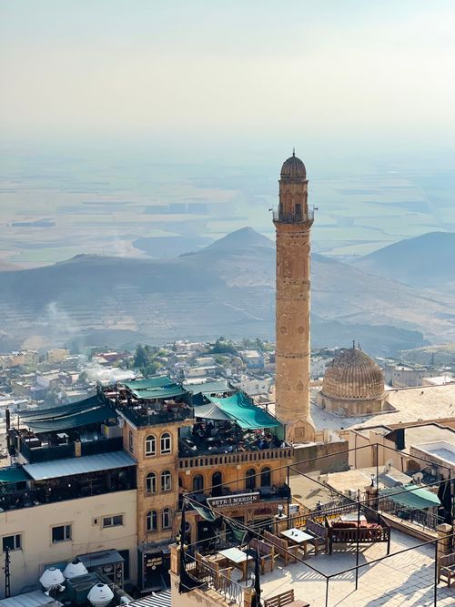 Free Beautiful aerial photo showcasing Mardin's iconic mosque minaret with scenic mountains in the background. Stock Photo