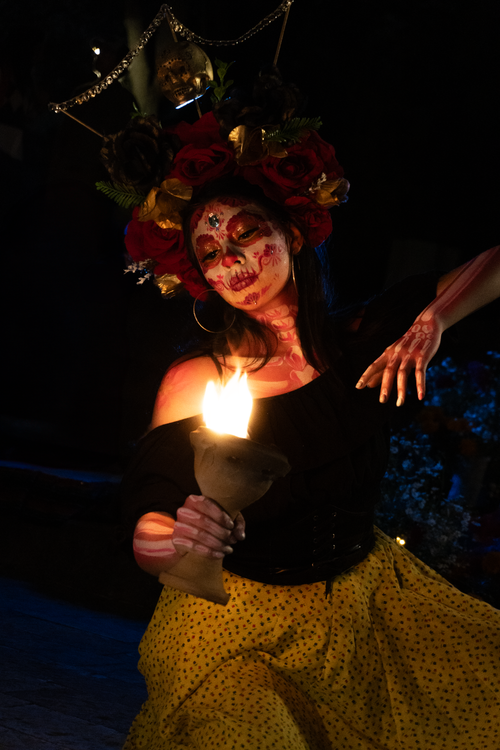 Free Artistic portrayal of a woman with face paint holding a flame in a dark setting. Stock Photo