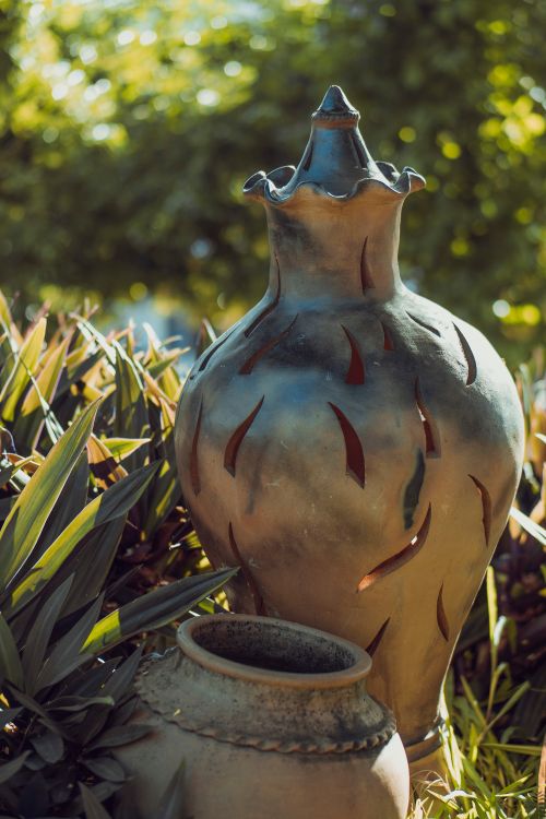 Free Close-up of artistic pottery vases in a sunlit garden amidst lush greenery. Stock Photo