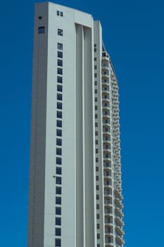 A modern skyscraper with a minimalist design against a vibrant blue sky.