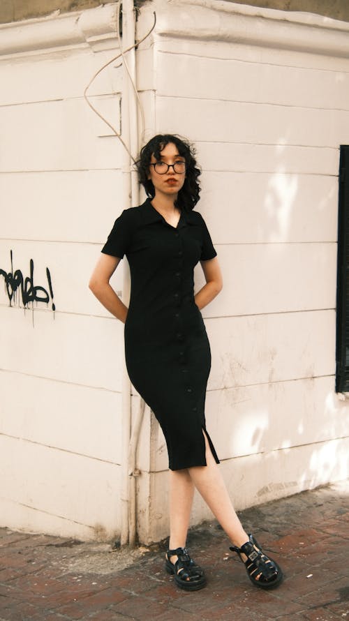 Woman in a Black Dress Leaning against a Building 