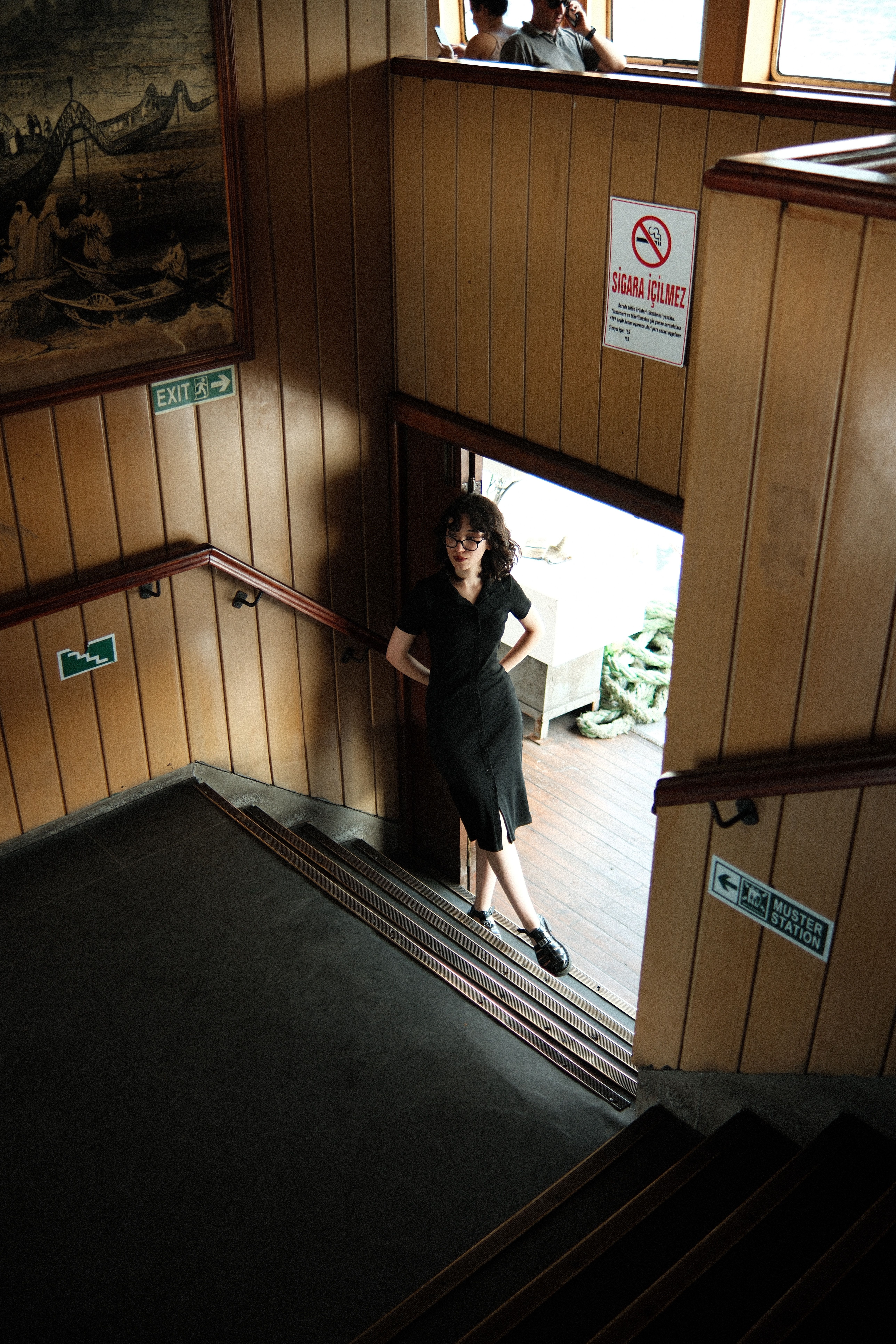 Casual portrait of a woman standing on a staircase in a wooden interior setting.