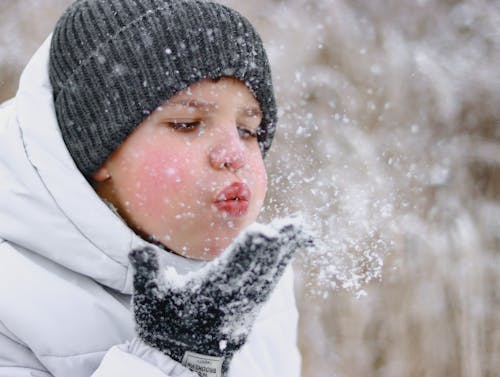 A Boy Blowing the Snow on His Hand 