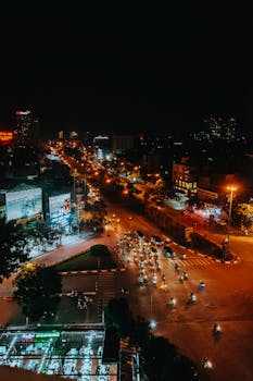 Aerial view of a bustling city intersection at night, showcasing vibrant streetlights and traffic.
