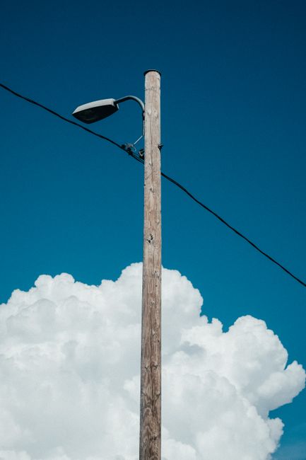 A streetlight pole with a blue sky and white clouds, captured in Helsinki, Finland.
