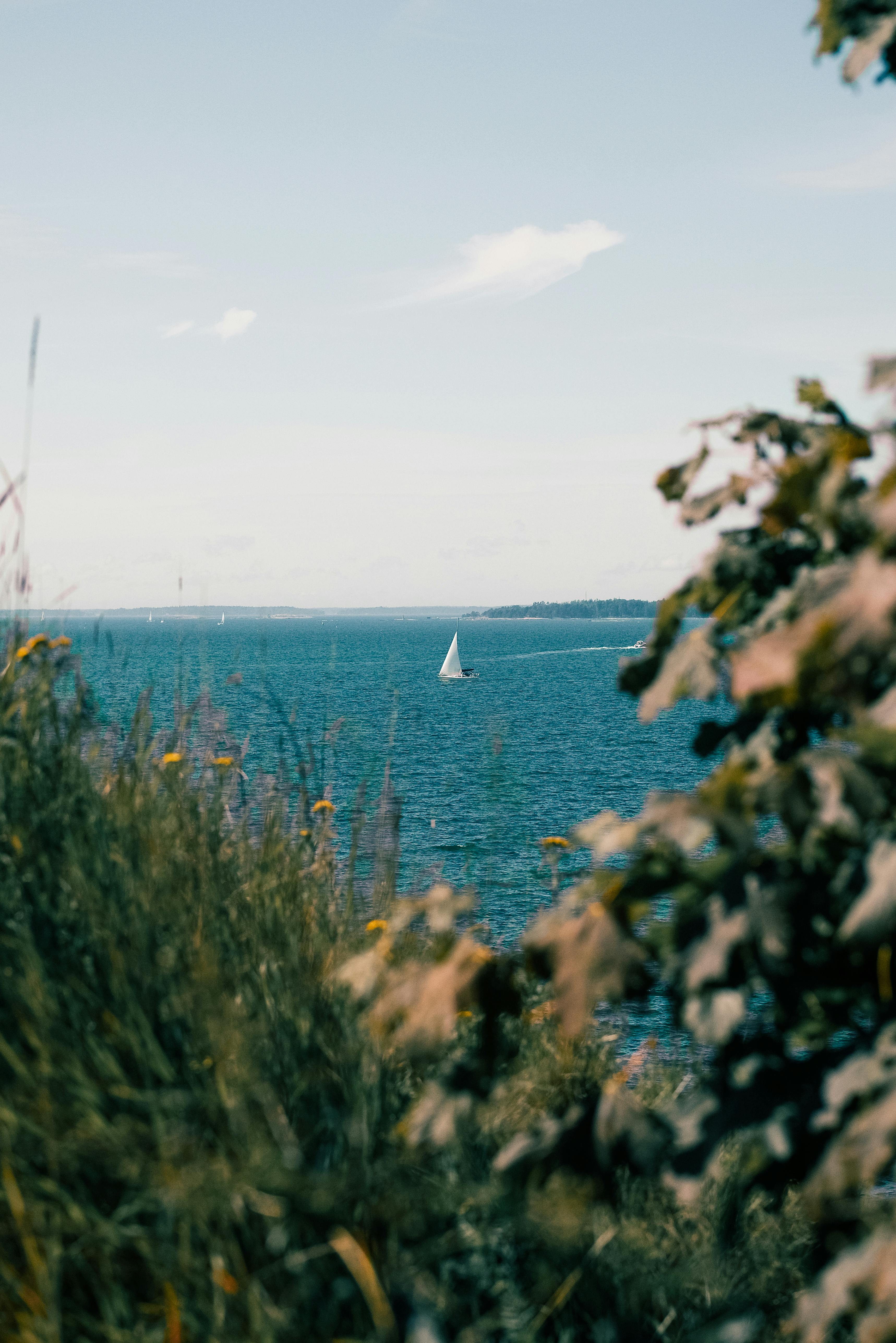 A serene sailboat gliding through the sea near Helsinki, Finland on a summer day.