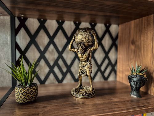 Free Stylish Atlas figurine and decorative plants on a wooden shelf, perfect for interior decor. Stock Photo