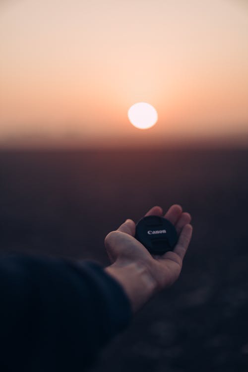 Man Holding Lens on a Field During Sunset 