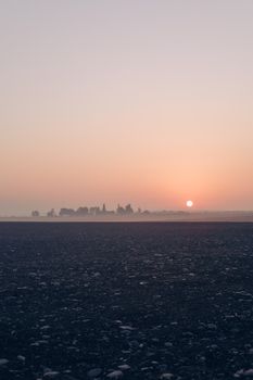 A tranquil sunset over a pebbled beach with a distant horizon, creating a calm and peaceful scene.