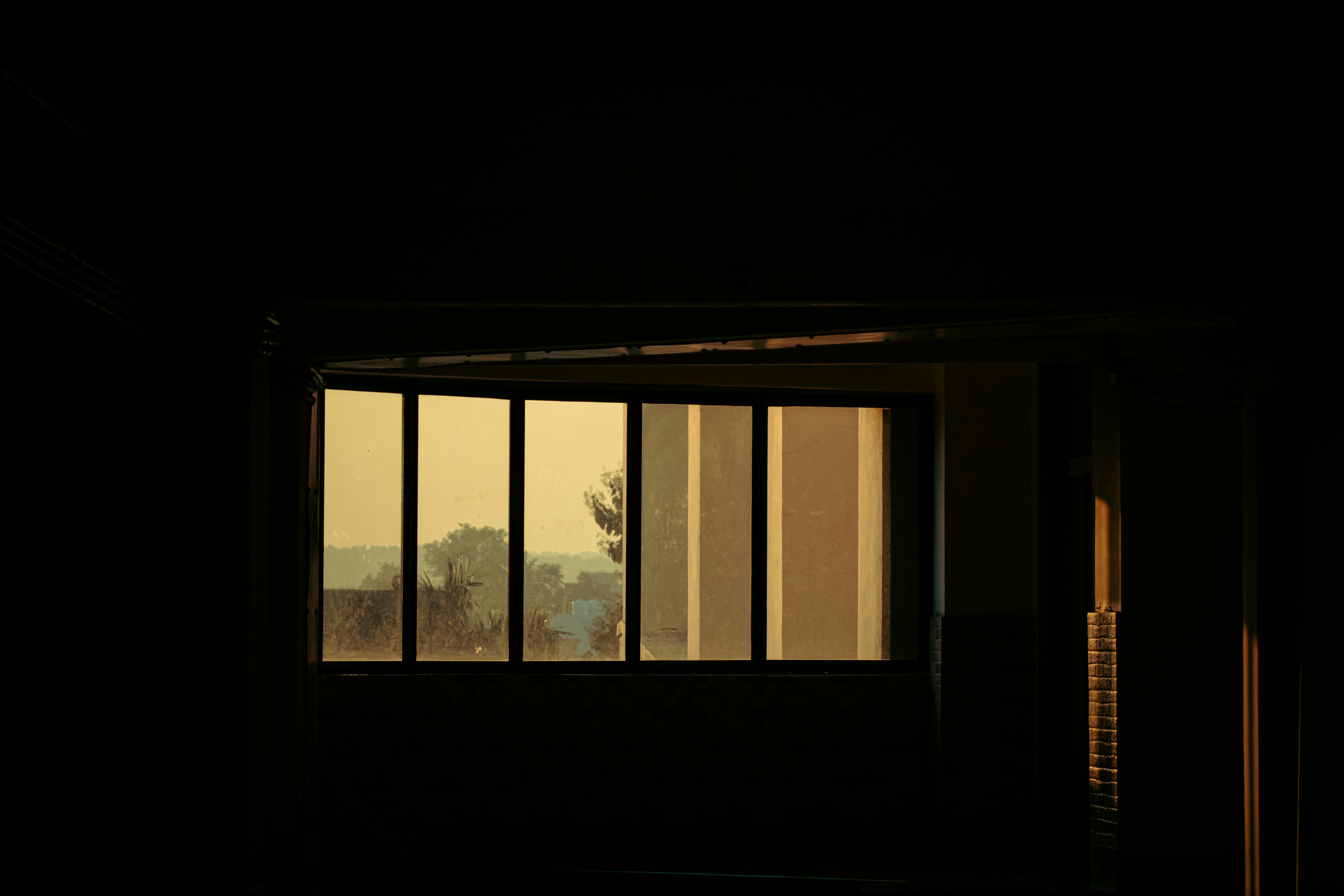 A low-lit Gangnam suite window showing seasonal foliage across the avenue at golden hour