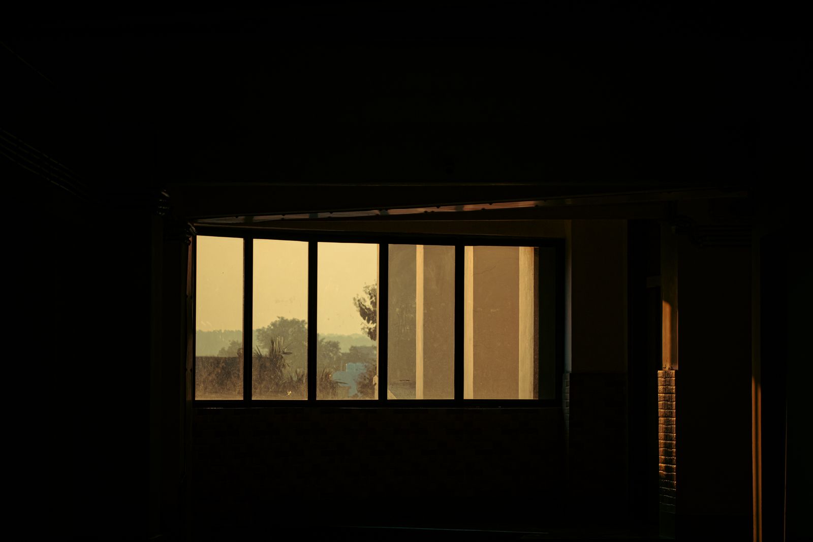 A lit window cutting a band of warm light through a dark room